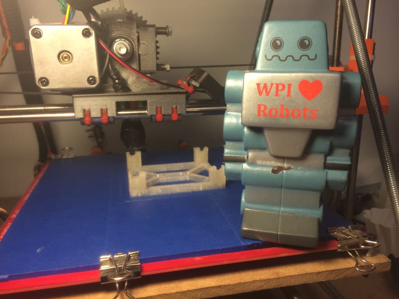 An Eraser Bracket used in the RBE 2002 (Sensing) Robot - along with a WPI Robotics Mascot.